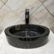 Black granite oval washbasin with polished finish and modern faucet.